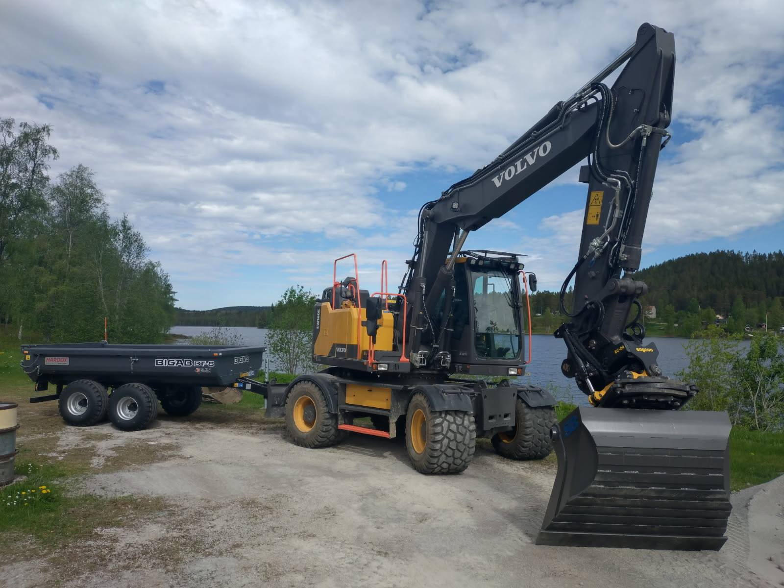 Hjulgrävmaskin med tiltrotator vid företagets släpvagn