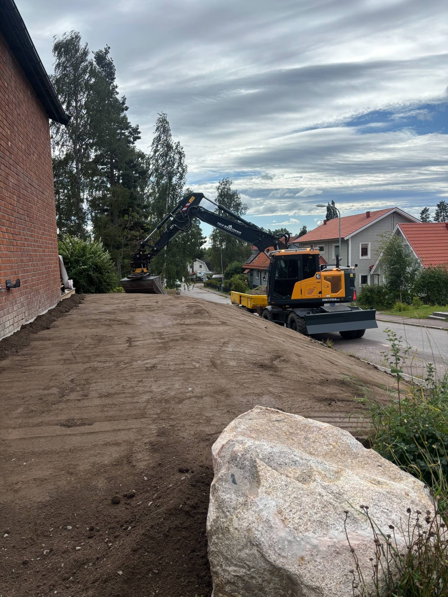 Grävmaskin som planar av en tomt i ett villakvarter